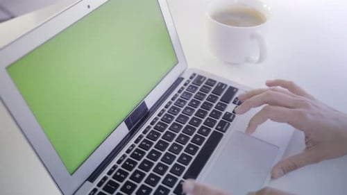 Young caucasian woman in her 30s using her laptop with a green screen to insert new content