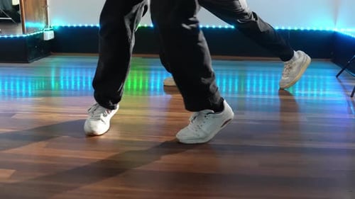 Feet Dancing in White Sneakers on Wood Floor