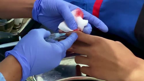 Medical Worker inserts Needle into Finger