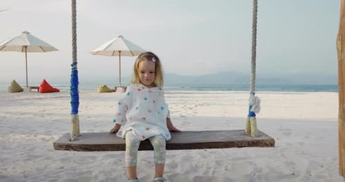 Happy Child Girl Plays on Swings on Tropical Beach Enjoy Childhood