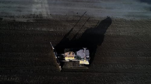 Bulldozer Plowing Dirt Field from Above