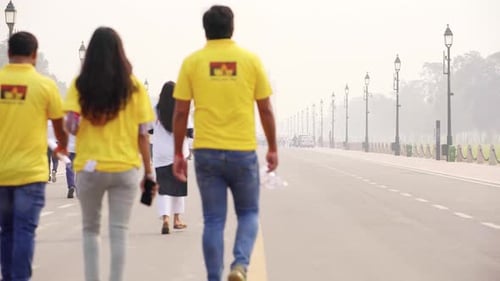 People Walking Down Street Towards Distant Monument