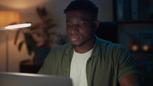Man Works on Laptop at Night at Home