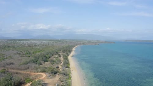 a landscape of a beautiful white sand beach and the ocean during a sunny day in a tropical area.