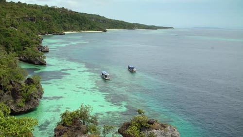 Ein Strand mit großen Felsen und segelnden Holzbooten