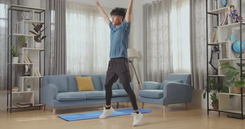 Athletic Fit Asian Man In Sportkleidung macht Jumping Jack Übungen zu Hause