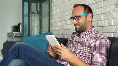 Man Using Tablet Device While Relaxing on Couch