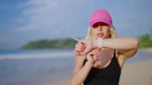 Young Blonde Woman Jogs By Sea at Sunrise Looks at Fitness Watch Caucasian Female Runs on Beach By