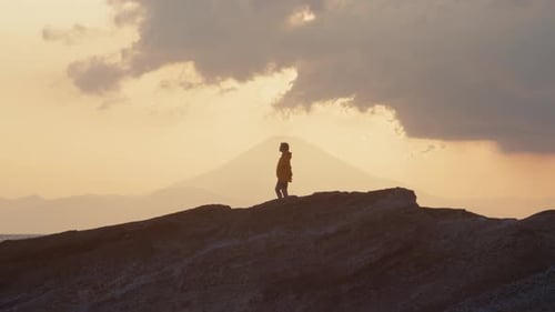Sunset Solitude – Woman on Rocky Japanese Coast