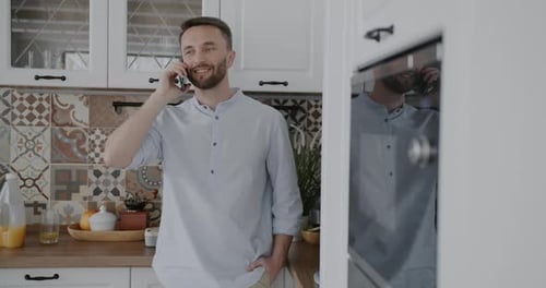 Man Chatting on Mobile Phone in Bright Kitchen