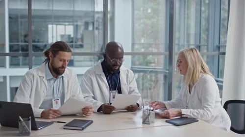 Group of Medical Workers Discussing Statistics of Their Clinic at Meeting