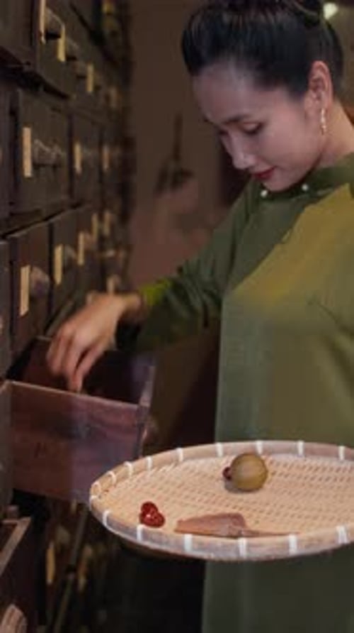 Vertical of Asian Woman Preparing Ingredients for Recipe at Herbal Apothecary