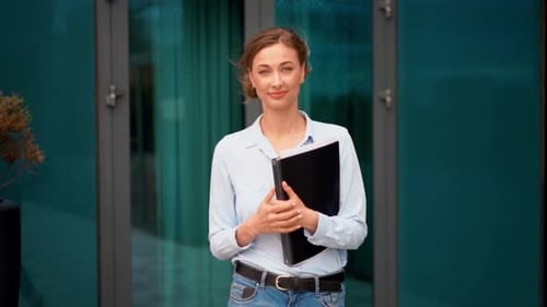 Confident Businesswoman Holding Folder While Walking Outside Office