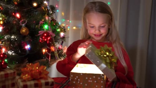 Girl Opens Christmas Present with Joyful Surprise