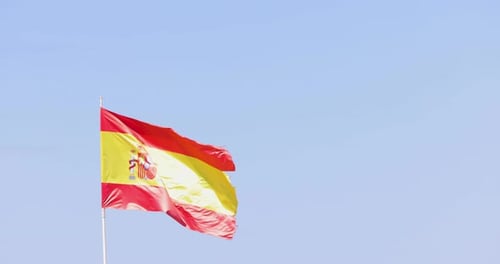 Spanish Flag Waving Against Blue Sky