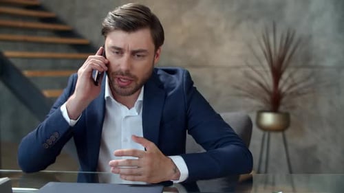 Closeup Stressed Business Man Talking On Mobile Phone In Office Emotionally. Disappointed Busines...