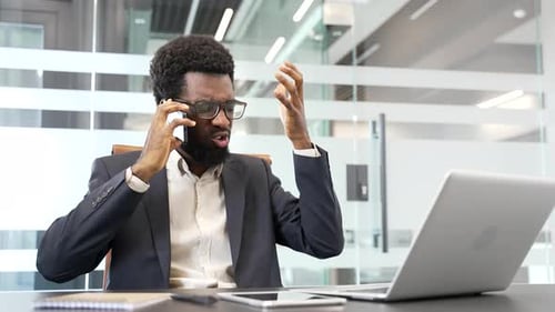 Frustrated Professional Arguing on Mobile Phone at Desk
