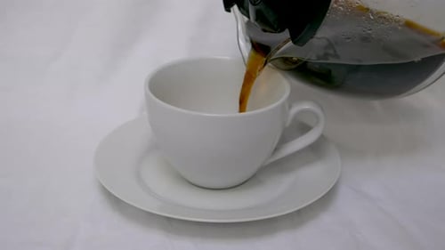 Pouring Coffee into a White Cup on Saucer