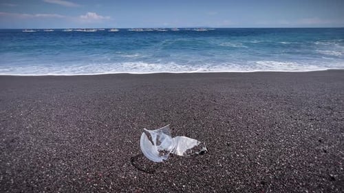 Wellen am sandigen Ufer mit Plastikmüll auf Bali, Indonesien. Nahaufnahme