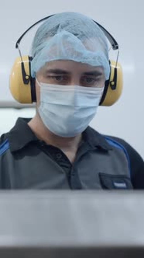Beer Factory Operators Wearing Headphones And Facemasks At Their Workplace Medium Shot