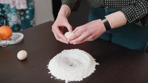 Adult Cracking Eggs into Flour for Cooking
