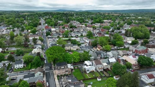 Colonial and Victorian houses and homes in small american town with green trees. Overcast clouds in