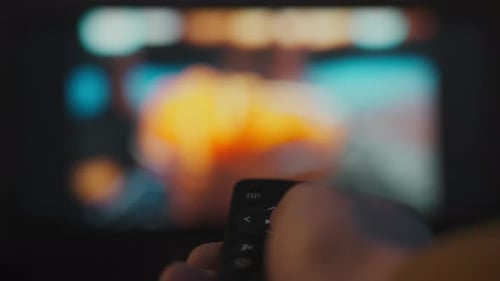 A young man spends the evening comfortably on the sofa in a home theater. With the remote control