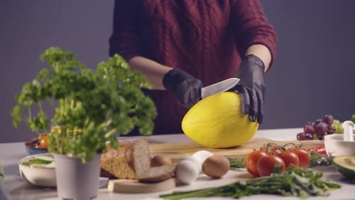 Koch schneidet eine frische gelbe Melone auf einem Holzschneidebrett