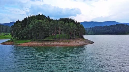 Lake with Clear Water and Stone Shore in Spruce Forest with Fir Trees Against a Daytime Sky