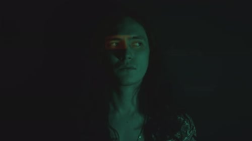 Young Man Looking at Side as Posing in Dark Studio with Blinking Light