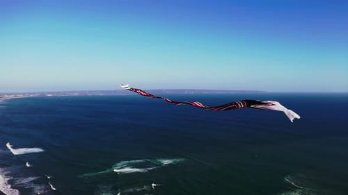Traditional balinese kite with long flowing tail flying high above sea.