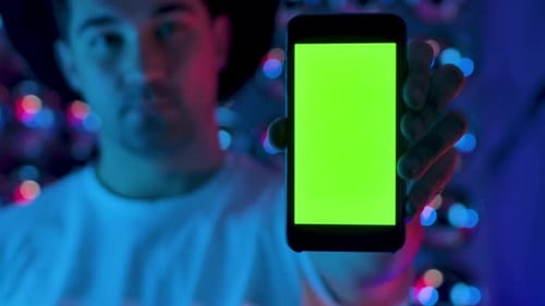 Creative Man Hand Holding a Mobile Telephone with Vertical Green Screen Mockup