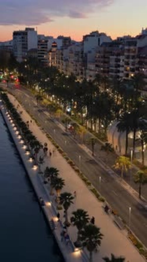 Aerial drone view of boats docked on the sea, near the streets of the city in the evening. Vertical