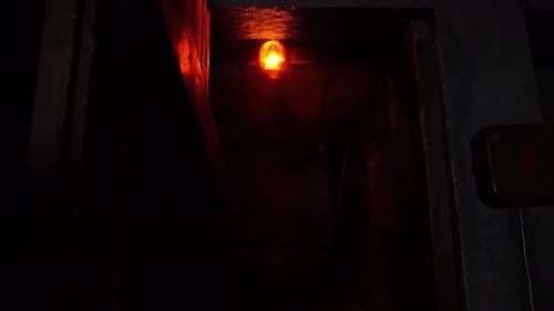 Closeup of a Rotating Red Emergency Siren Lamp on the Wall of a Dark Tunnel