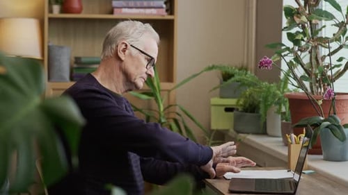 Senior Man Talking during Online Session with Psychologist in Green Home Office