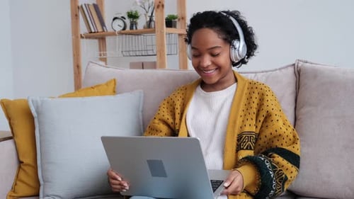 Young Woman Using Laptop on Sofa at Home