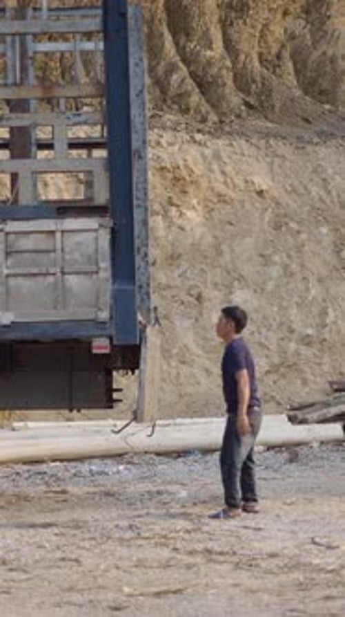 Driver of a Large Asian Truck Opens the Tailgate of the Box to Load It with Trunks in Vietnam