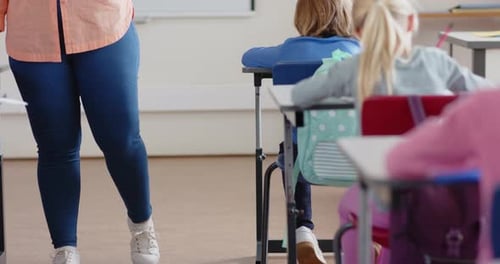 In school, female teacher using tablet while assisting student in classroom