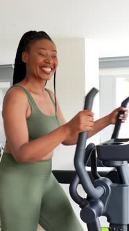Woman Smiling While Exercising on Elliptical Machine