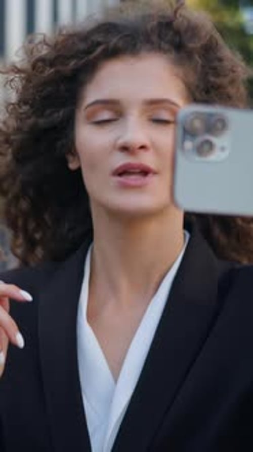 Mujer de negocios caucásica hablando por videollamada con teléfono móvil grabando un vlog caminando por el centro