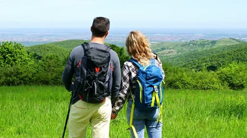 Rear view of young couple enjoying hiking together in nature.