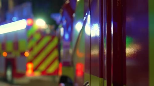 Emergency Lights Flashing on Fire Trucks Parked in Residential City Area During Nighttime Response