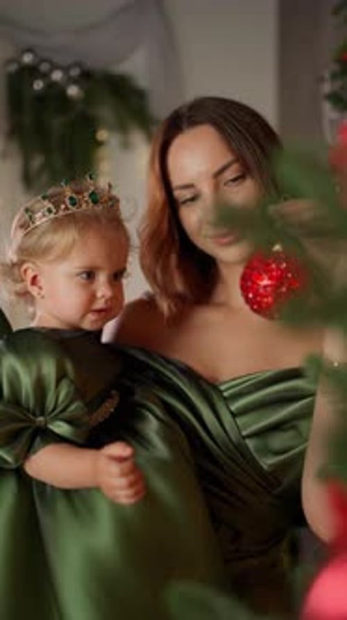Baby in Mother's Arms Looking at Christmas Tree Decorations Family New Year Concept