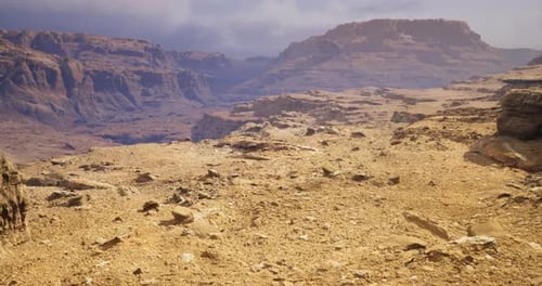 Vast Desert Landscape Under a Cloudy Sky Showcasing Rugged Mountains and Rocks