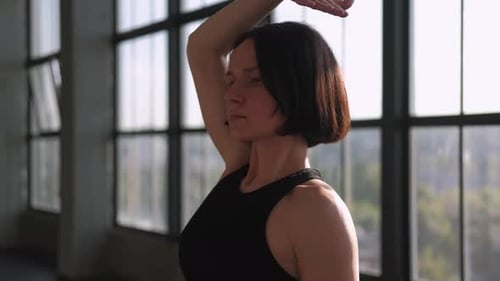 Woman Stretching Neck Indoors on a Sunny Day