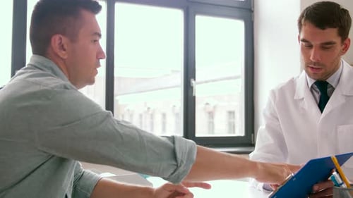 Doctor Talking with Patient at Desk in Office