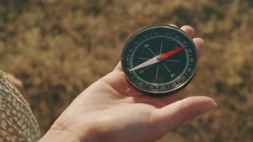 A CloseUp Detailed View of a Compass Gripped in Hand While Standing on a Sunny Open Field