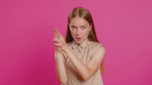 Junge Frau zeigt mit Fingerpistole herum, trifft Wahl, schießt mit Handpistole