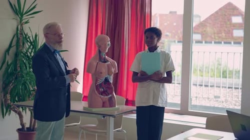 Medical Teacher Explains Anatomy to Student with Mannequin