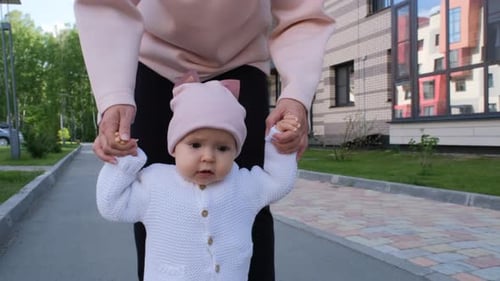 Infant Taking First Steps with Adult Assistance